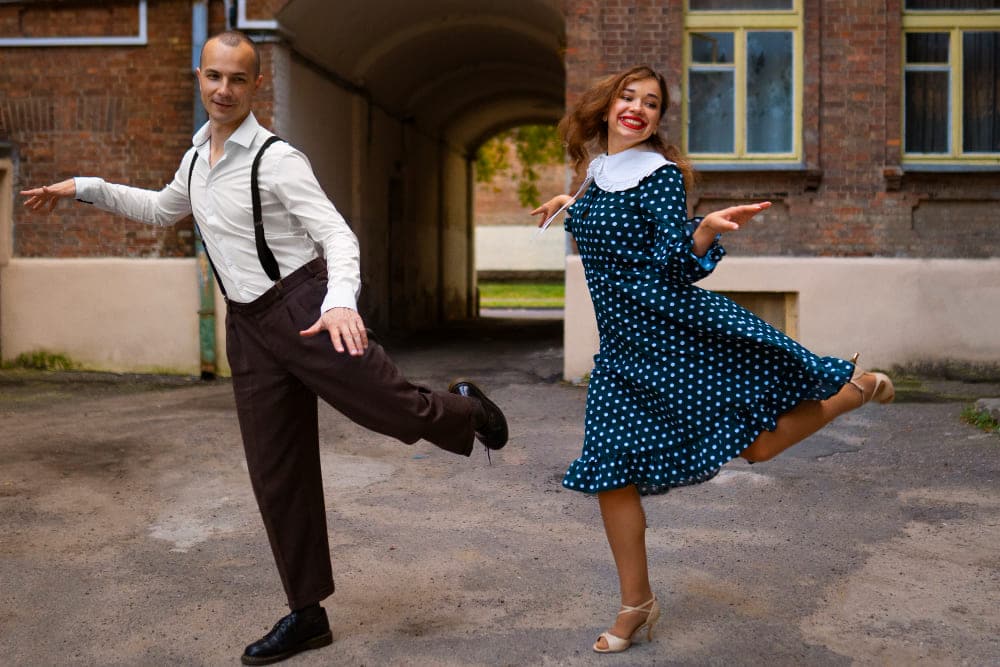 pareja bailando en callejon con ropa retro en actitud alegre durante evento cultural